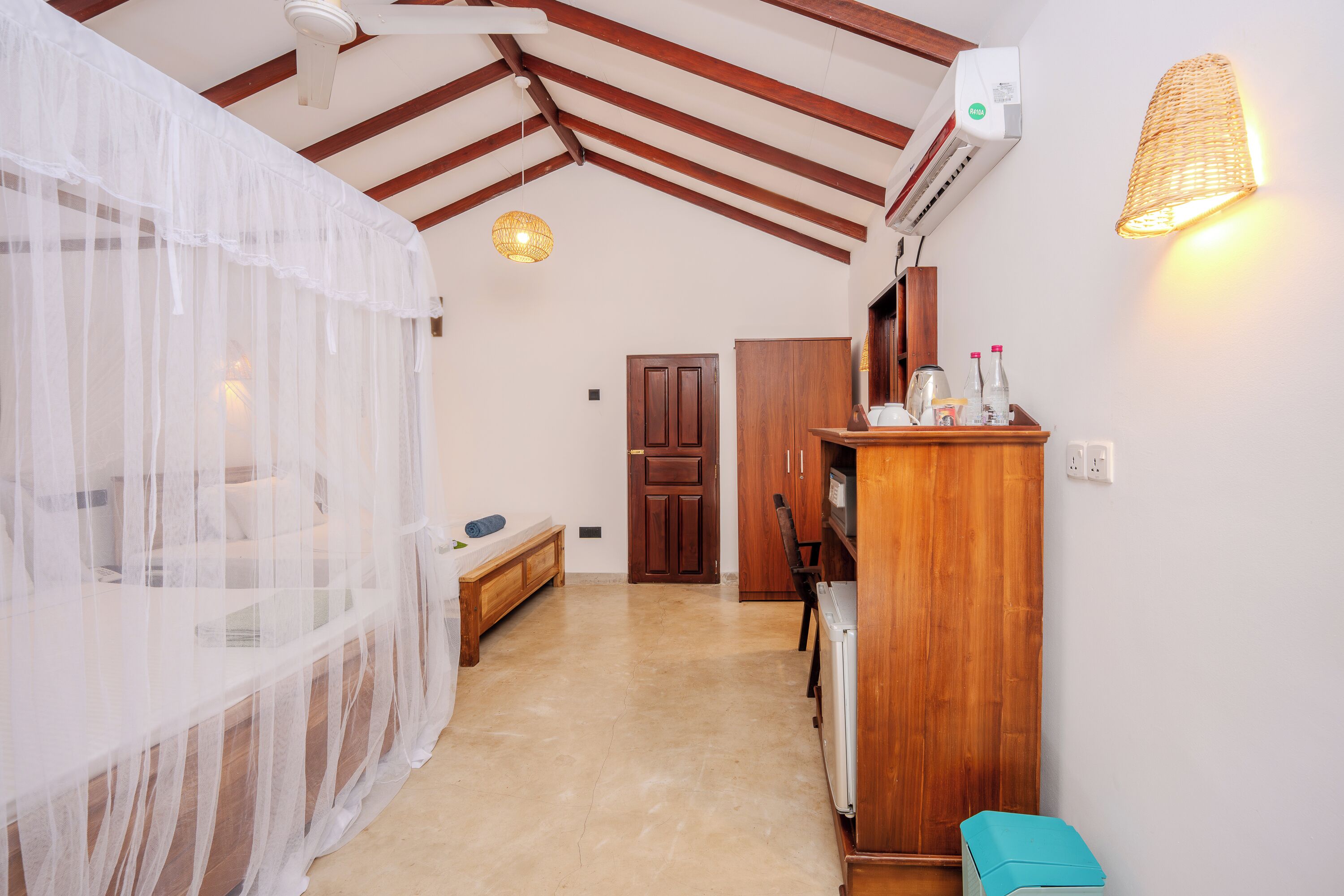 A bedroom with a canopy bed, a wooden wardrobe, a bench, and a small stool.