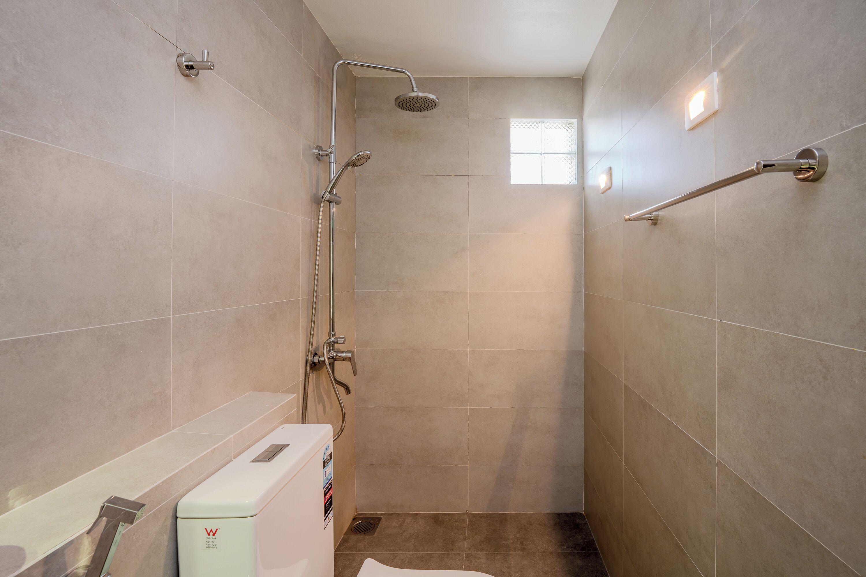 Une petite salle de bain moderne avec une douche à l’italienne, des toilettes et un porte-serviettes.