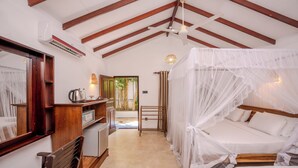 A bedroom with a canopy bed, wooden beams, a desk with a chair, and a view of the outdoors. - Central Beach Inn (Mirissa)