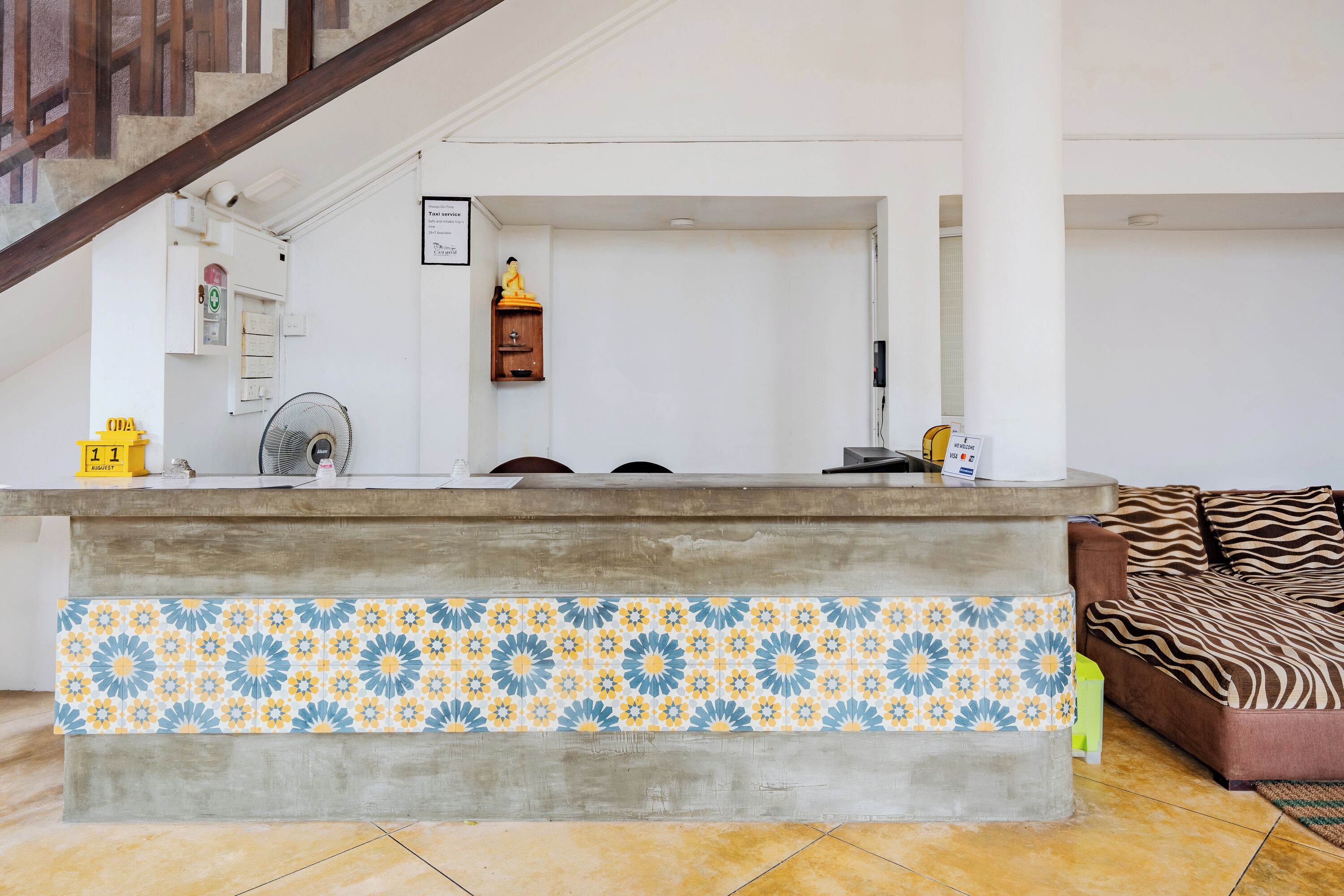 Uma área de recepção com balcão revestido de azulejos, um sofá e uma escada.