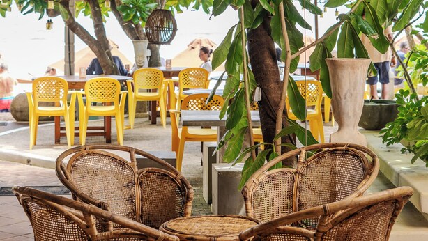 An outdoor seating area with wicker furniture and hanging lights, surrounded by greenery. - Central Beach Inn (Mirissa)