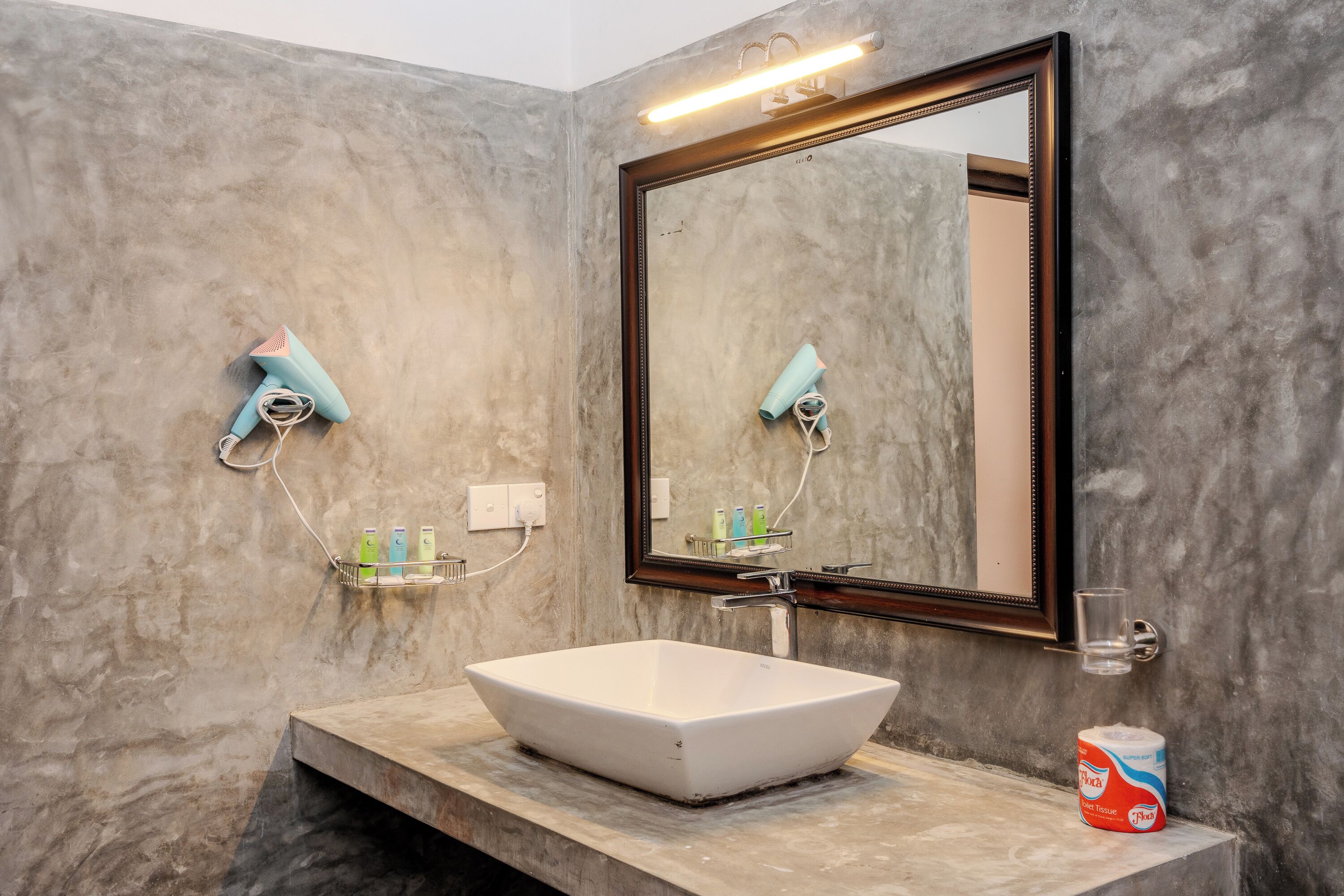 A bathroom with a large mirror, a white vessel sink, a towel rack, and a hand dryer.