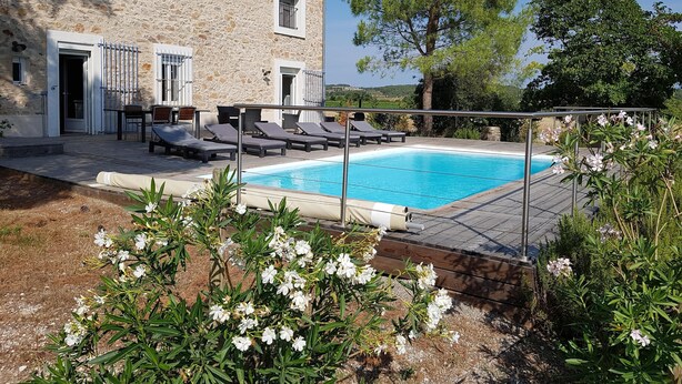 A stone building with a swimming pool, outdoor seating, and a view of the countryside.