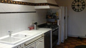 A kitchen with white cabinets, a double sink, a stove, and a clock on the wall.