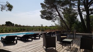 A wooden deck with lounge chairs and a pool.