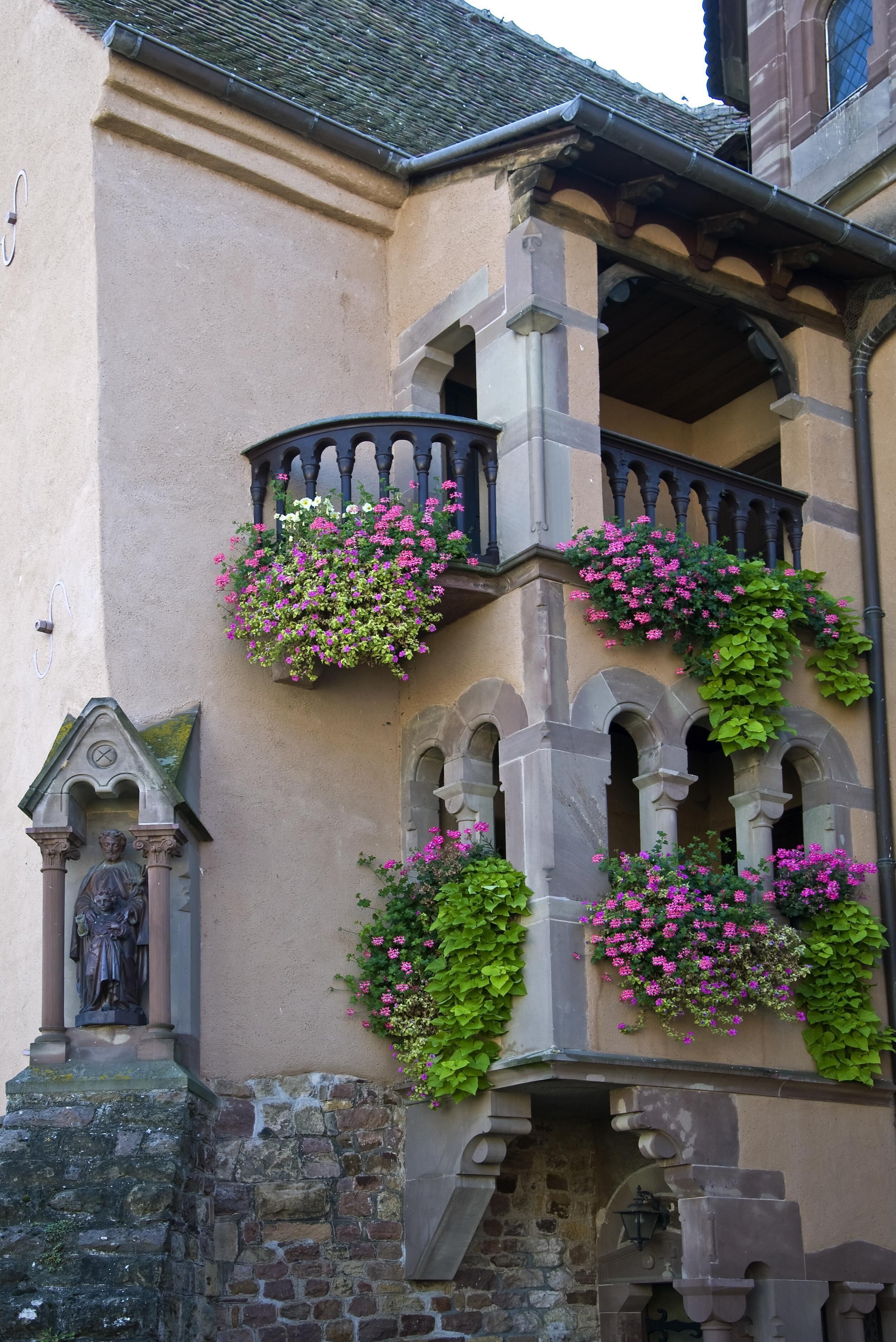 A building with a stone facade, arched windows, and flower boxes on the balconies.