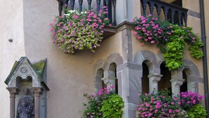 Ein Gebäude mit einer Stein-Fassade, Bogenfenstern und Blumenkästen an den Balkonen.