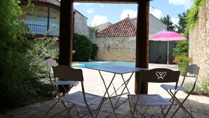 Une terrasse extérieure avec une piscine, des murs en pierre et une pergola en bois.