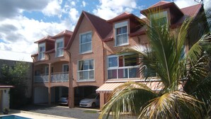 A multi-story building with a swimming pool in the foreground. - apartment rental Le Tampon (Réunion) (LE TAMPON)