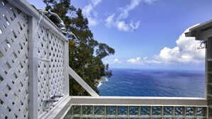 Un balcone con vista sull'oceano e un recinto in legno bianco.