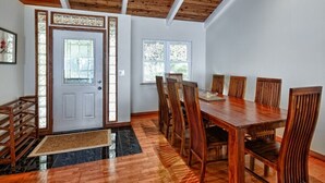 Un'area pranzo con tavolo e sedie in legno, soffitto in legno e una porta con pannelli di vetro.