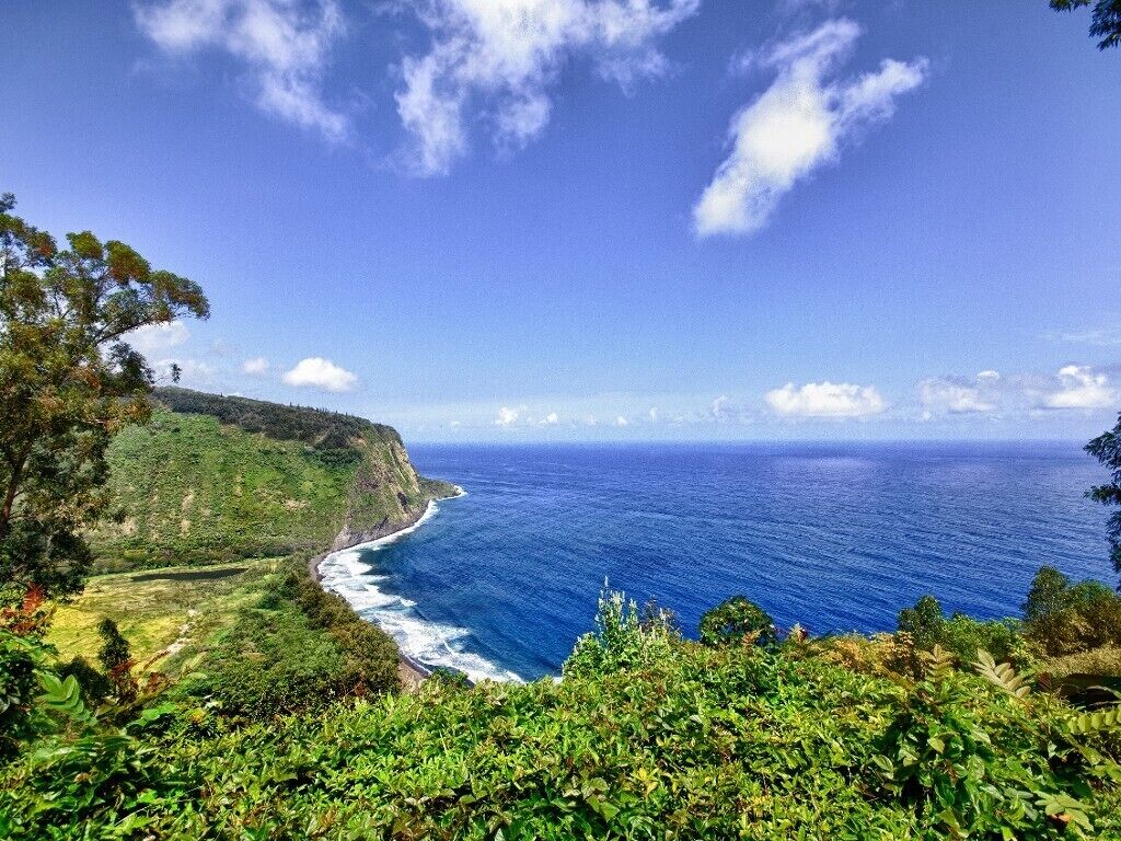 A coastal landscape with a view of the ocean and a green hillside.
