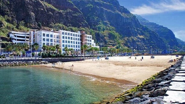 A coastal hotel with a beach view, a rocky shoreline, and a mountainous backdrop. - Amazing views, large terrace and garden. (Madère)