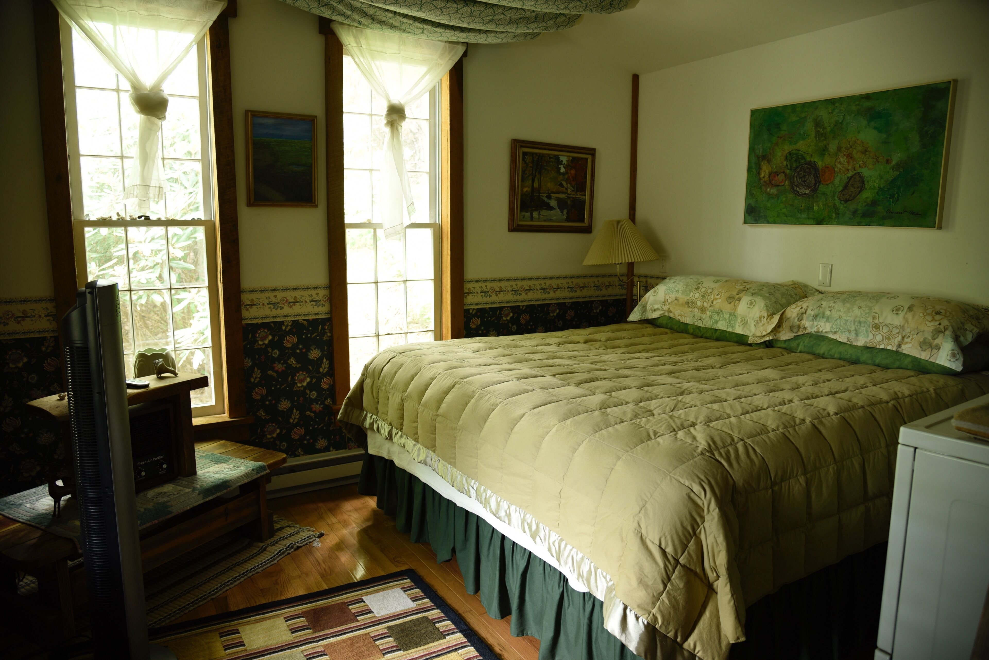 A room with a bed, a desk, a chair, a lamp, and a painting on the wall.