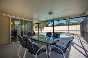 A glass-top table with chairs, a pool, and a sliding glass door leading to a patio area.