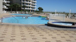 Relax by the pool, surrounded by lounge chairs and umbrellas, with a hot tub nearby.