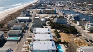 Vista aérea de un pueblo costero con propiedades frente a la playa, un puerto deportivo y una playa.