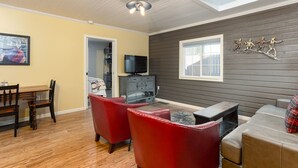 Una sala de estar con piso de madera, televisor, chimenea y sofá rojo.