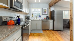 Una cocina moderna con electrodomésticos de acero inoxidable, armarios blancos y suelo de madera.