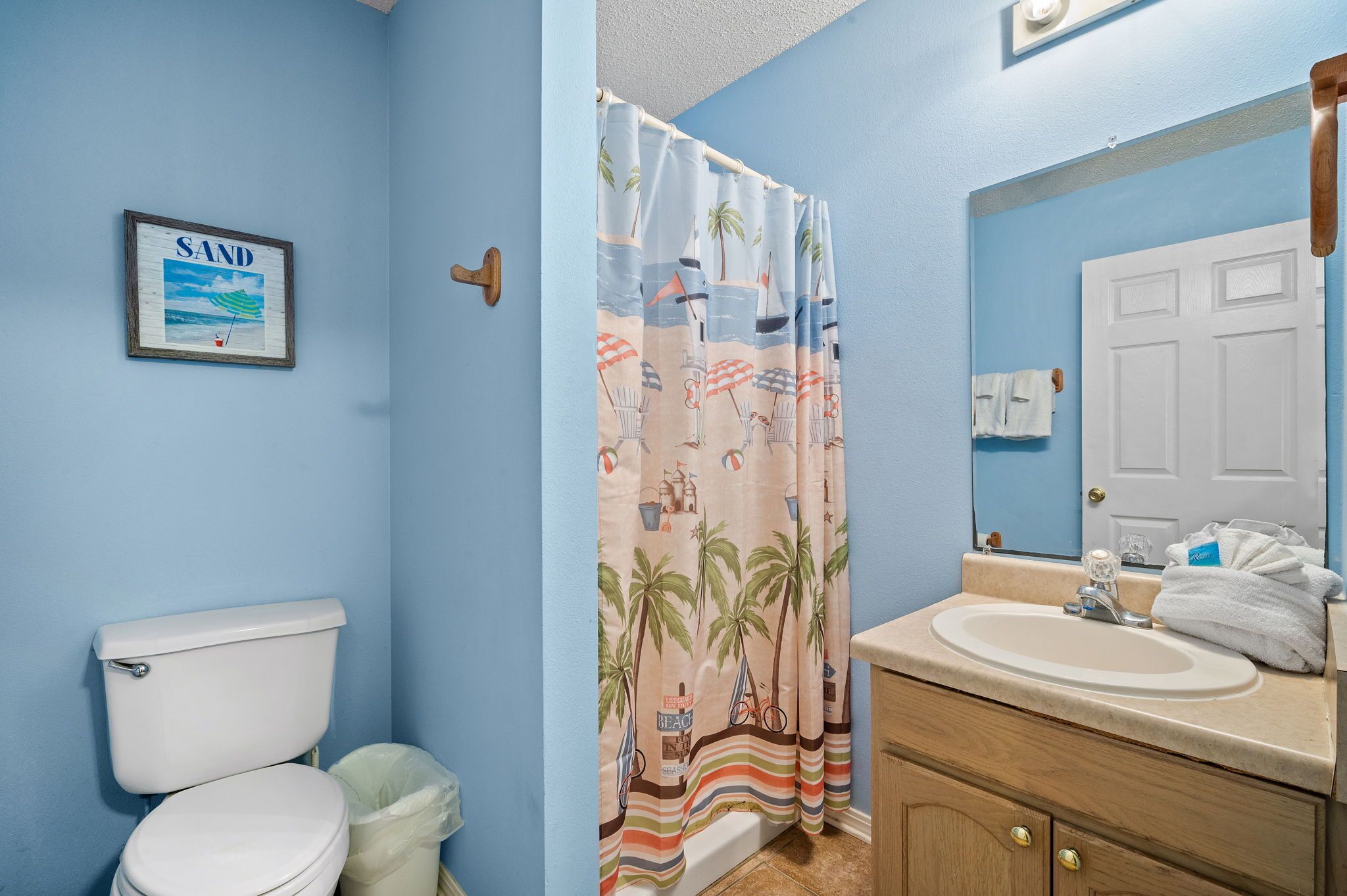 Ein Badezimmer mit Toilette, Waschbecken und einer Duschvorhang mit Strandmotiv.