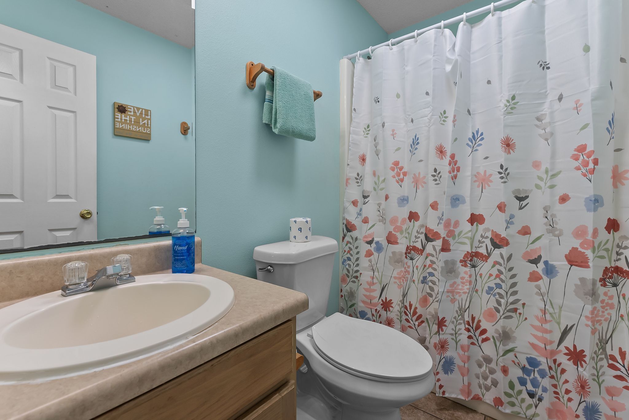 A bathroom with a sink, toilet, and shower curtain.