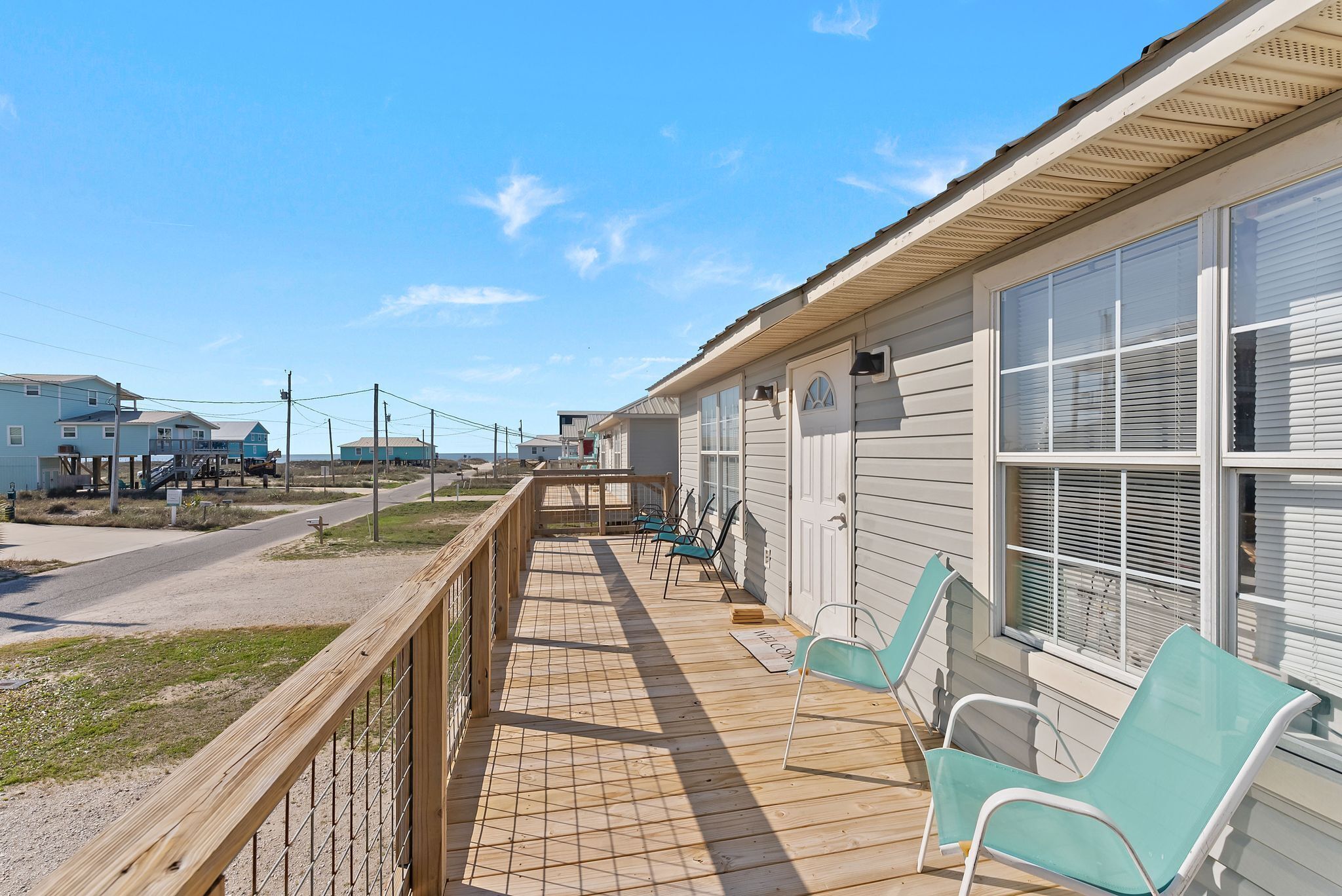 A wooden deck with chairs, a building with large windows, and a clear sky.