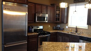 A modern kitchen with stainless steel appliances, granite countertops, and wooden cabinets. - Private Lakeside, private Dock, Outddor Kitchen Fire Pit & More (Chappells)