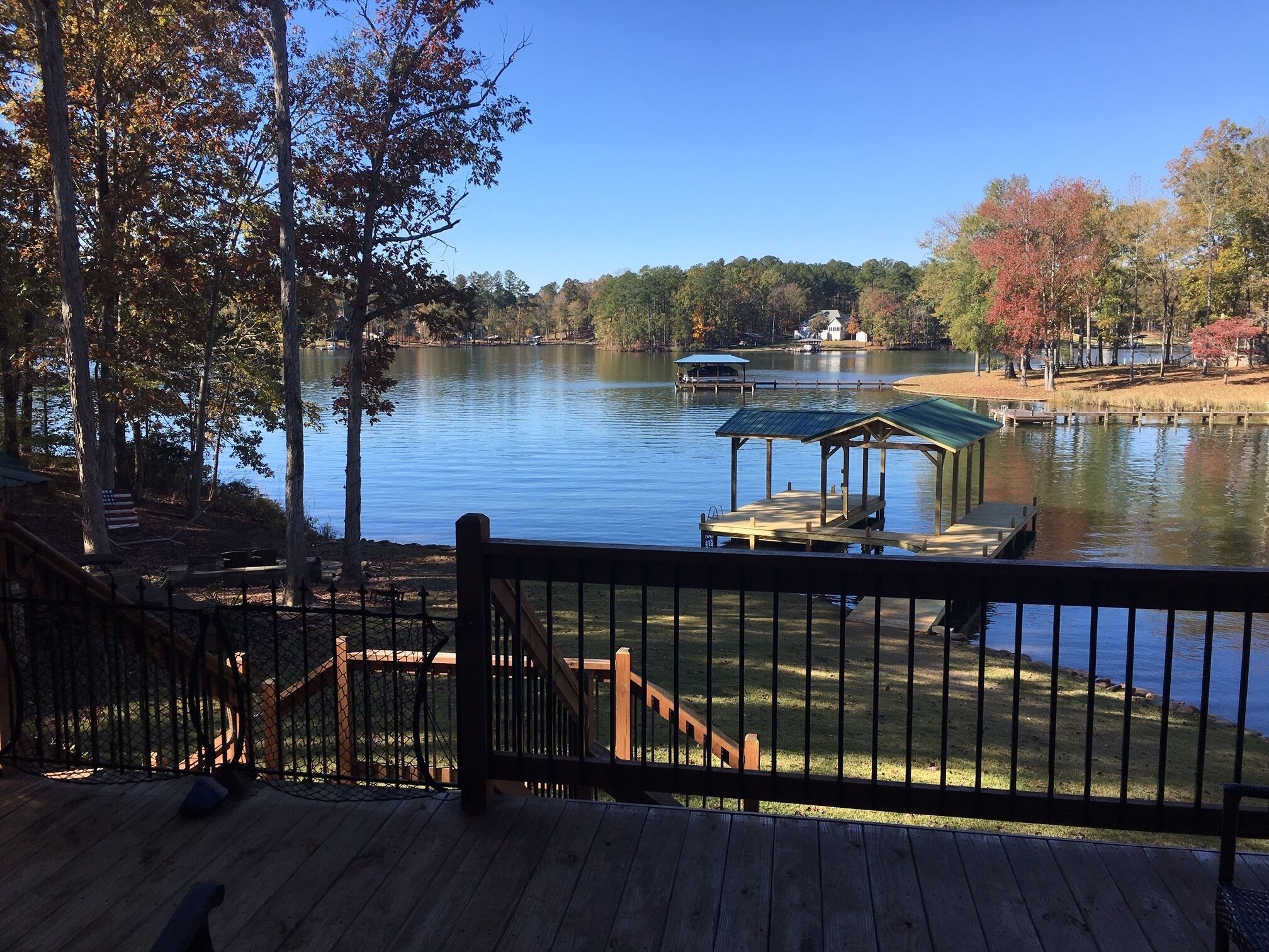 A lakeside deck with a gazebo, dock, and a view of the lake and surrounding trees.