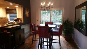 Ein Essbereich mit Tisch und Stühlen, einer Chandelier und Blick ins Freie.
