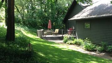 A house with a covered patio, a lawn, and a large tree in the foreground.