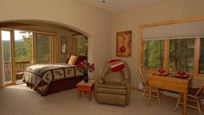 Un dormitorio con una cama grande, una silla, un escritorio y vistas al exterior.