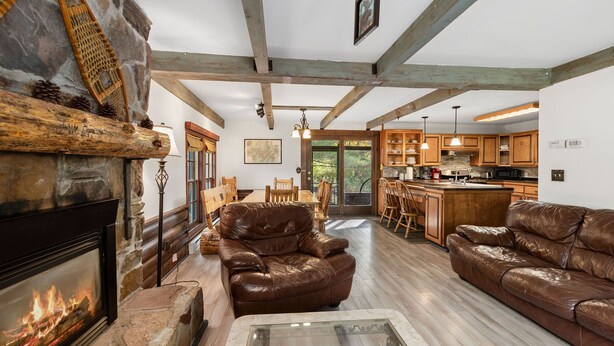 A spacious living room with a fireplace, leather sofas, and a stone fireplace surround. - Secluded Family Getaway Cabin near Whiteface (Upper Jay)
