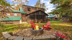 A log cabin with a stone fire pit and red Adirondack chairs. - Secluded Family Getaway Cabin near Whiteface (Upper Jay)
