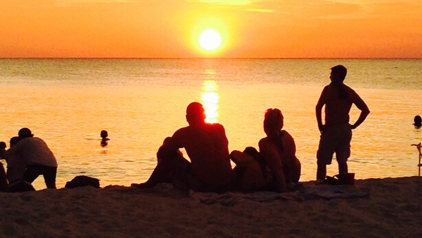 A sunset over a beach with people sitting and standing on the sand. - Coastal Cottage near beaches, dining & shopping! (Naples)