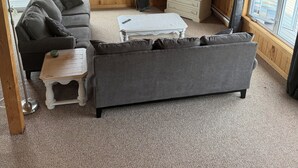 A cozy cabin interior with a wooden ceiling, a sofa, a coffee table, and a TV area. - Ocean Edge Beach House (Malpeque)