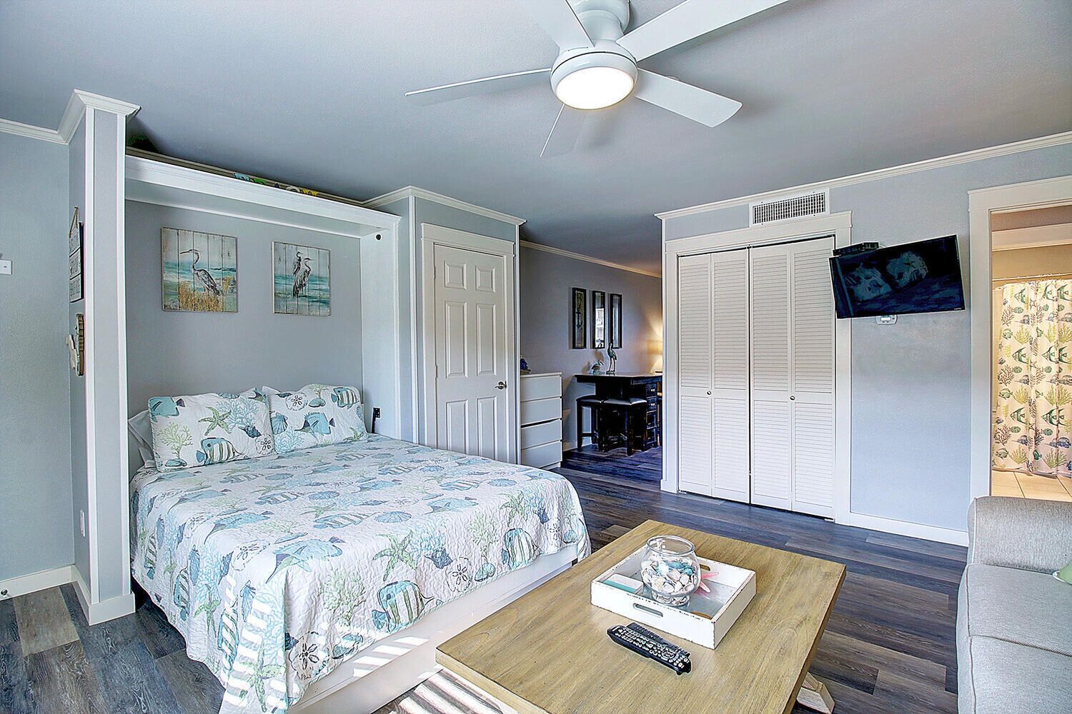Un dormitorio con cama, escritorio, armario y ventilador de techo.