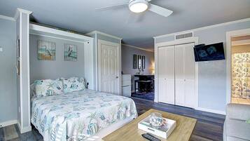 Un dormitorio con cama, escritorio, armario y ventilador de techo.