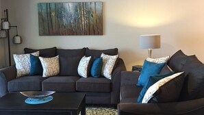 Ein Wohnzimmer mit Deckenventilator, zwei Sofas mit gemusterten Kissen, einem Couchtisch und einem Teppich.