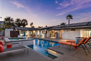 A modern outdoor pool area with lounge chairs and a small hot tub.