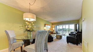 A living room with a glass dining table, two grey armchairs, a sofa, and a large window with a view. - Amazing View - On Golf Course - Near Beaches, Shopping & Restaurants (Venice)