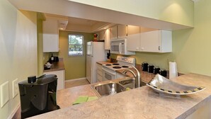 A compact kitchen with white cabinets, a microwave, a stove, and a sink. - Amazing View - On Golf Course - Near Beaches, Shopping & Restaurants (Venice)