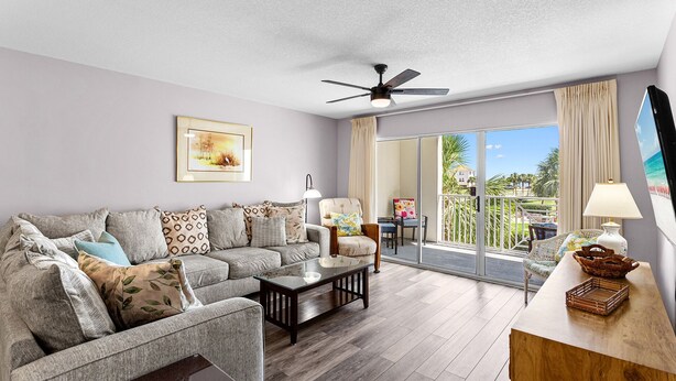 A living room with a sofa, armchairs, a coffee table, a ceiling fan, and a view of the outdoors through a sliding glass door. - Amalfi Coast 213B - Community Pool, Fitness Facility, Gulf Views, Miramar Beach! (Miramar Beach)