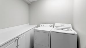 A laundry room with a washing machine and dryer, white walls, and a countertop. - Amalfi Coast 213B - Community Pool, Fitness Facility, Gulf Views, Miramar Beach! (Miramar Beach)