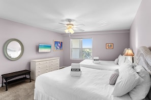 A bedroom with two beds, a ceiling fan, a TV, and a window with a view.