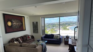 Un salon spacieux doté d’une grande fenêtre donnant sur un paysage côtier.
