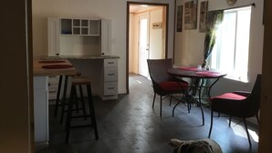 A kitchen with white cabinets, a dining area with a table and chairs, and a ceiling fan. - Charlie’s house on the lake (Nikiski)