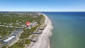 Luftaufnahme einer Küstenlandschaft mit Strand, Gebäuden und einem markierten Ort.