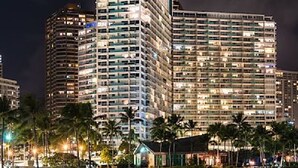 A high-rise hotel with multiple floors, large windows, and a well-lit facade. - Unobstructed Ocean View Suite. Don't miss out on the last-minute special rate! (Honolulu)