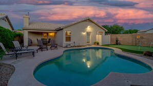 A backyard with a swimming pool, lounge chairs, and a small patio area. - 3BR w pool, putting green, fire pit (Gilbert)