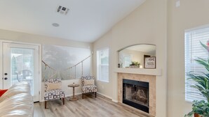 A spacious living room with a fireplace, a hanging chair, and a sofa. - 3BR w pool, putting green, fire pit (Gilbert)